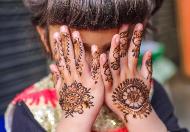 A Kashmiri girl poses for a photograph as she shows her henna painted hands at a market ahead of Eid al-Fitr holiday, in Srinagar, the summer capital of Indian Kashmir, 08 April 2024. Eid al-Fitr is an Islamic holiday that marks the end of Ramadan, and is celebrated during the first three days of Shawwal, the 10th month of the Islamic calendar. It is expected to begin on 10 or 11 April 2024, depending on the lunar calendar. (Photo by Farooq Khan/EPA)