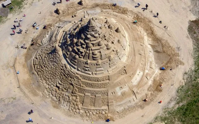 Sand carvers work on a giant sand castle on display at the sand sculptures festival in Binz on the Baltic Sea island of Ruegen, northeastern Germany, on June 5, 2019. Artists try to get an entry in the Guinness World Records with the record castle that has a height of 17,5 meters. (Photo by Jens Büttner/dpa/AFP Photo)