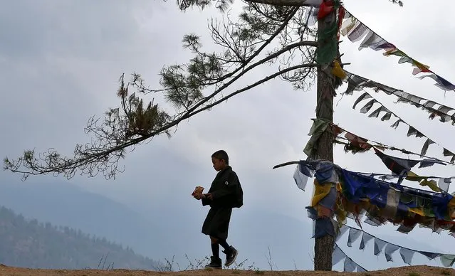 A boy in a traditional costume walks past prayer flags in Thimphu, Bhutan, April 16, 2016. (Photo by Cathal McNaughton/Reuters)