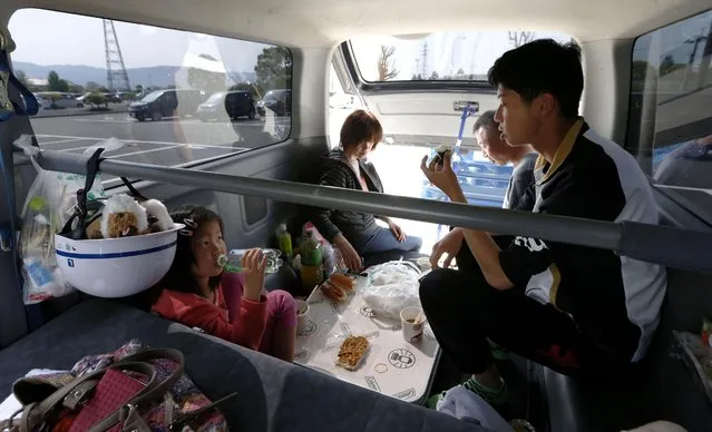 A family eats rations inside their vehicle where they have sheltered for three days in the earthquake-hit Mashiki, Kumamoto prefecture, Japan Tuesday, April 19, 2016. More than 100,000 evacuees, some sleeping in their cars and others in gymnasiums or community centers, were bracing for another chilly night. Many people are afraid to stay in their homes as aftershocks continued to shake the area on the southern island of Kyushu, including a 5.5-magnitude temblor Tuesday afternoon. (Photo by Naoya Osato/Kyodo News via AP Photo)