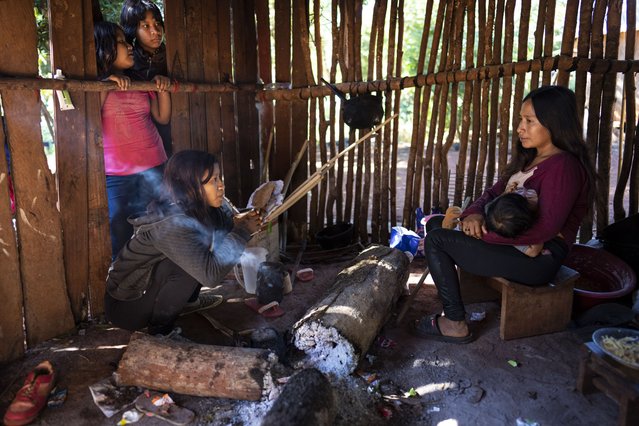 Margarita Mendez, front left, drinks mate as her friend Cristina Chamorro breastfeeds in an outdoor kitchen in the Guaraní Indigenous community of Kaaguy Pora II, on the outskirts of Andresito, in Argentina's Misiones Province, the center of the world's maté production, April 18, 2024. (Photo by Rodrigo Abd/AP Photo)