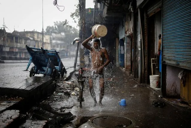 A man bathes at a roadside in a market area after authorities in the capital ordered a weekend curfew, following the rise in the coronavirus disease (COVID-19) cases, in the old quarters of Delhi, India, January 8, 2022. (Photo by Adnan Abidi/Reuters)