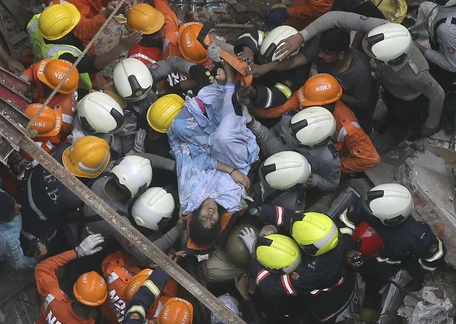 Rescuers carry out a survivor from the site of a building that collapsed in Mumbai, India, Tuesday, July 16, 2019. A four-story residential building collapsed Tuesday in a crowded neighborhood in Mumbai, India's financial and entertainment capital, and several people were feared trapped in the rubble, an official said. (Photo by Rajanish Kakade/AP Photo)