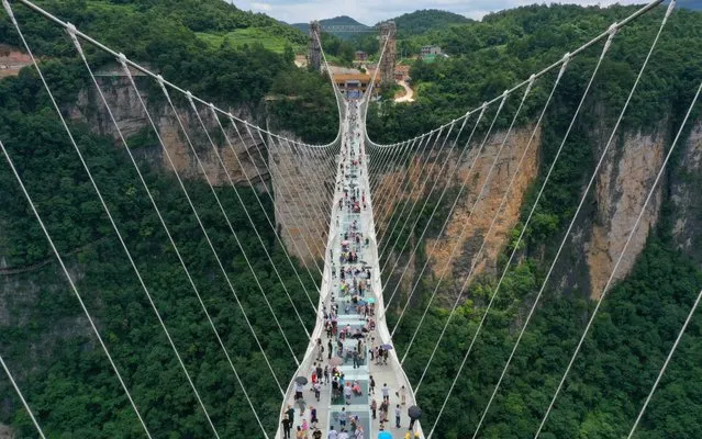 Tourists walk on the world's longest and highest glass-bottomed bridge over the Zhangjiajie Grand Canyon at Wulingyuan Scenic and Historic Interest Area in Zhangjiajie city, central China's Hunan province, 27 July 2019. (Photo by Imaginechina via AP Images)