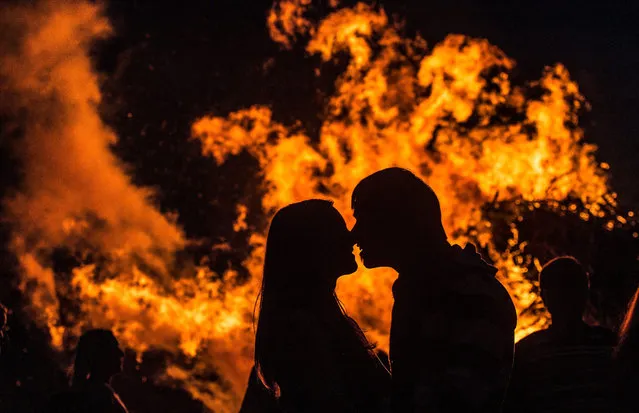 A picture dated 21 June 2015 shows a couple kissing in front of a midsummer bonfire at Mundenhof in Freiburg, Germany. The event is celebrated on the longest day and the shortest night of the year. (Photo by Patrick Seeger/EPA)