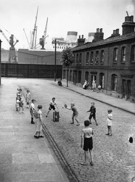 Children playing cricket in a street in Millwall, east London, UK  15th August 1938. A liner on the Thames is in the background. (Photo by Fox Photos/Getty Images)