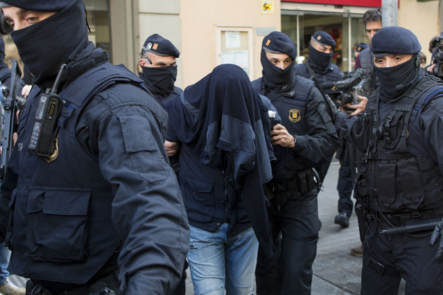 Members of the Catalan Regional Police (Mossos d' Esquadra) arrest a man (C) accused of collaborating with the Islamic militants, after searching a flat in Barcelona on April 25, 2017 Spanish police today arrested four men over their alleged links to suspects arrested in Belgium over their alleged involvement in the Brussels airport and metro attacks last year, officials said. (Photo by Josep Lago/AFP Photo)