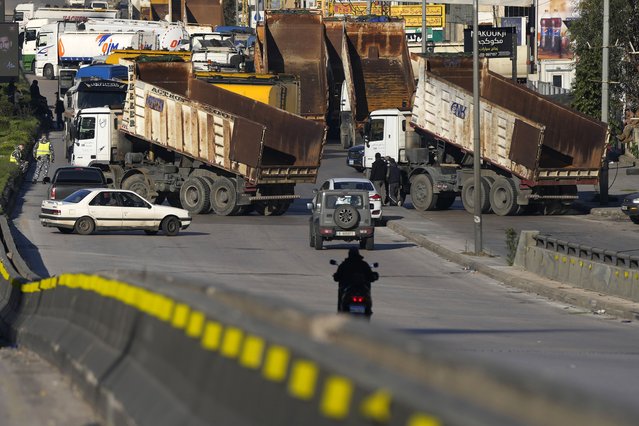 Dump trucks block a main highway during a general strike by public transport unions protesting the country's deteriorating economic and financial conditions in Beirut, Lebanon, Wednesday, February 2, 2022. (Photo by Hassan Ammar/AP Photo)