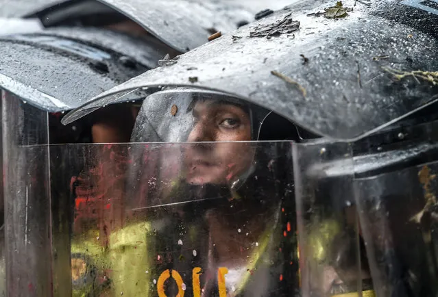 Riot police take cover behind their shields assuming a Romans-like tortoise formation as they clash withopposition activists during a protest against the government in Caracas on May 12, 2017. Daily clashes between demonstrators -who blame elected President Nicolas Maduro for an economic crisis that has caused food shortage- and security forces have left 38 people dead since April 1. Protesters demand early elections, accusing Maduro of repressing protesters and trying to install a dictatorship. (Photo by Juan Barreto/AFP Photo)
