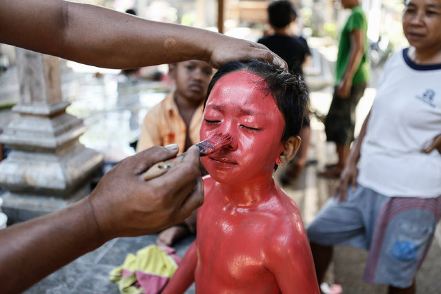 A boy have their face painted in preparation for the Grebeg ritual on June 25, 2014 in Tegallalang Village, Gianyar, Bali, Indonesia. During the biannual ritual, young members of the community parade through the village with painted faces and bodies to ward off evil spirits. (Photo by Putu Sayoga/Getty Images)