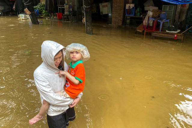 A woman holds a boy as she wades through a flooded street following the impact of Typhoon Yagi, in Thai Nguyen City, Vietnam on September 11, 2024. (Photo by Thinh Nguyen/Reuters)