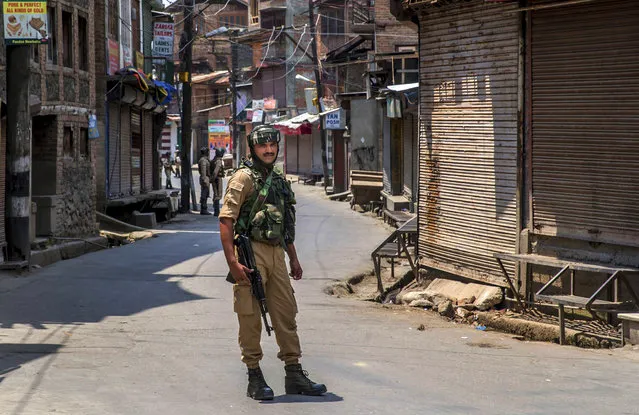 An Indian paramilitary soldier stands guard on a deserted street in Srinagar, Indian controlled Kashmir, Friday, July 7, 2017. Government forces imposed curfew-like restrictions in many parts of Indian controlled Kashmir to stop anti Indian protests ahead of the first death anniversary of rebel leader Burhan Wani on Saturday. His killing by security forces last year sparked violent street clashes and almost daily protests throughout the region. (Photo by Dar Yasin/AP Photo)