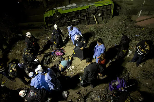 In this Sunday, July 9, 2017 photo, rescue workers and police work the scene after a deadly bus accident in Lima, Peru. Peruvian officials said a double-decker tour bus went out of control and rolled over on a narrow road in the hills. (Photo by Rodrigo Abd/AP Photo)