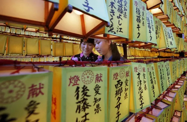 Women walk in front of a row of paper lanterns with the names of the shrine deveotees, during the festival of “Mitama” or departed souls, at Yasukuni shrine in Tokyo, Monday, July 14, 2014. The annual summer festival is held to solace the souls of the war dead. (Photo by Shizuo Kambayashi/AP Photo)