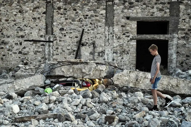 A boy stands next to a car crushed under rubble near the port of the Greek island of Kos following a 6.5 magnitude earthquake which struck the region on July 21, 2017. Two foreigners died and more than 100 people were injured on the Greek island of Kos when an earthquake shook popular Greek and Turkish holiday destinations in the Aegean Sea. The epicentre of the 6.7 magnitude quake was some 10.3 kilometres (6.4 miles) south of the major Turkish resort of Bodrum, a magnet for holidaymakers in the summer, and 16.2 kilometres east of the island of Kos in Greece, the US Geological Survey said. (Photo by Louisa Gouliamaki/AFP Photo)