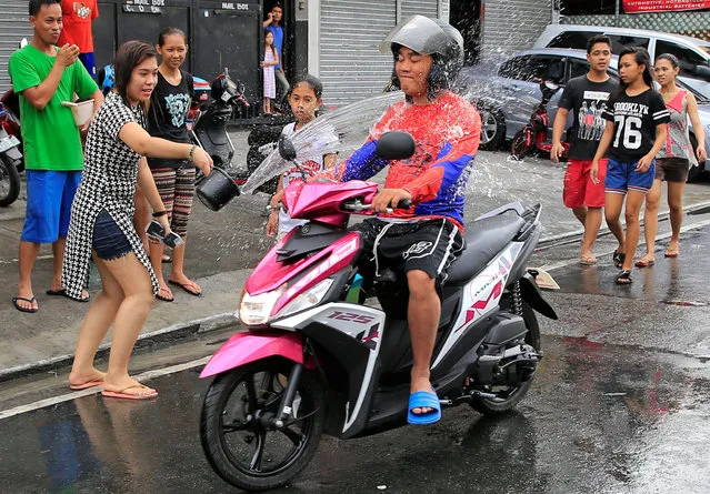 A woman throws a bucket of water at a motorcyclist as residents join in a water-splashing frenzy to honor their patron St. John the Baptist's Feast Day in San Juan, Metro Manila, Philippines June 24, 2016. (Photo by Romeo Ranoco/Reuters)