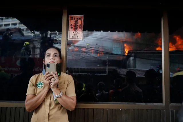 A woman watches Thai firefighters put out a fire that broke out at a house in central Bangkok, Thailand, 21 June 2022. According to local residents, the fire broke out at a wooden home which soon spread to neighboring residences. Firefighters at the scene said that the fire destroyed at least 10 homes in the Bon Kai community, and fortunately there were no casualties. A member of the fire brigade received a minor injury to his leg while attempting to put out the fire, and was quickly helped out by fellow firefighters.The exact cause of the fire was still being investigated. (Photo by Diego Azubel/EPA/EFE/Rex Features/Shutterstock)