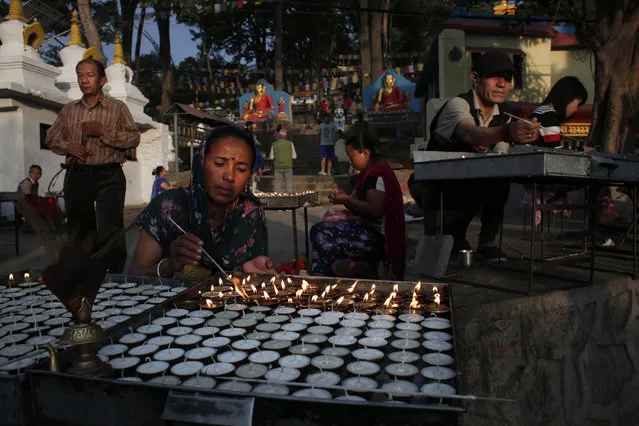 Buddhist worshippers light butter lamps during morning prayers in Swayambhunath stupa, Kathmandu, Nepal, Tuesday, June 13, 2017. Swayambhunath stupa is an ancient religious complex atop a hill also known as the monkey temple. (Photo by Niranjan Shrestha/AP Photo)