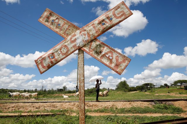 A child holds an umbrella as he stands on SGR railway tracks near the town of Kiu, south of Nairobi, Kenya, December 16, 2019. The new $3.3 billion high-speed railway, part of China's “One Belt, One Road” initiative, has left towns like Kiu without stations or adequate service, its residents say. (Photo by Baz Ratner/Reuters)