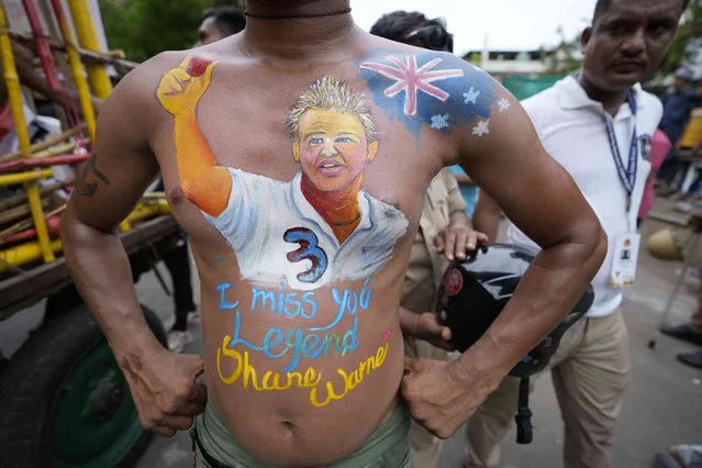 A devotee has his body painted with the portrait of Australian cricketer late Shane Warne during an annual Rath Yatra, or Chariot procession of Lord Jagannath, in Ahmedabad, India, Friday, July 1, 2022. Three idols of Hindu God Jagannath, his brother Balabhadra and sister Subhadra are taken out in a grand procession in specially made chariots called raths, which are pulled by thousands of devotees. (Photo by Ajit Solanki/AP Photo)