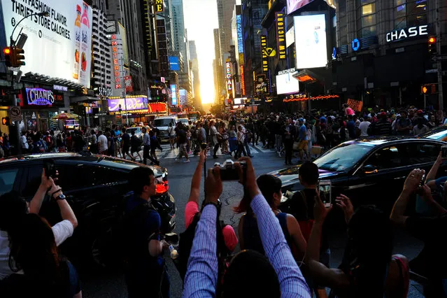 People take pictures as the sun sets over Manhattan aligned exactly with the streets in a phenomenon known as “Manhattanhenge”, in New York City, U.S., July 11, 2016. (Photo by Mark Kauzlarich/Reuters)