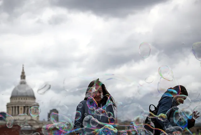People walk through soap bubbles in front of St Paul's Cathedral in London, Britain, May 27, 2019. (Photo by Hannah McKay/Reuters)