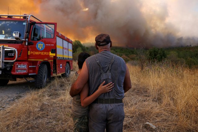 Panagiotis Arabatzis, 57, hugs his son Stamatis, 13, as they watch smoke rising from a wildfire burning near the village of Lefkimi in the region of Evros, Greece on September 2, 2023. (Photo by Alexandros Avramidis/Reuters)