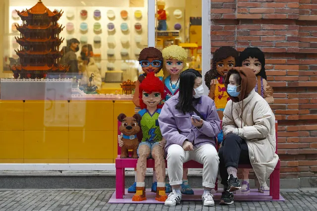 In this photo released by Xinhua News Agency, women wearing protective masks to prevent the new coronavirus outbreak chat with each other outside a Lego store at a re-opened commercial street in Wuhan in central China's Hubei province on Monday, March 30, 2020. Shopkeepers in the city at the center of China's virus outbreak were reopening Monday but customers were scarce after authorities lifted more of the anti-virus controls that kept tens of millions of people at home for two months. (Photo by Shen Bohan/Xinhua via AP Photo)