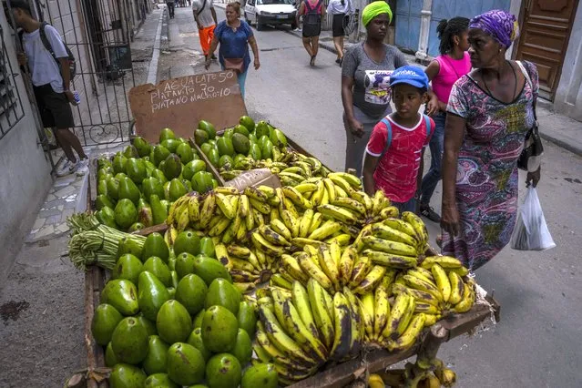 People walk past a vendor's cartful of fruit in Havana, Cuba, Saturday, July 9, 2022. The overall economy in Cuba remains dire, with long lines and rapidly rising prices for limited goods. (Photo by Ramon Espinosa/AP Photo)