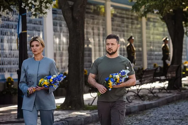 This handout photo taken and released by the Ukrainian presidential press service on August 24, 2022, shows Ukrainian President Volodymyr Zelensky (R) and his wife Olena attending a commemoration ceremony at a memorial wall displaying images of Ukrainian servicemen and servicewomen killed since Russia launched a military invasion on the country in February, in the centre of Kyiv, on Ukraine's Independence Day. Ukraine's Independence Day also marks six months since the start of Moscow's military invasion launched on February 24. (Photo by Ukraine Presidency/AFP Photo)