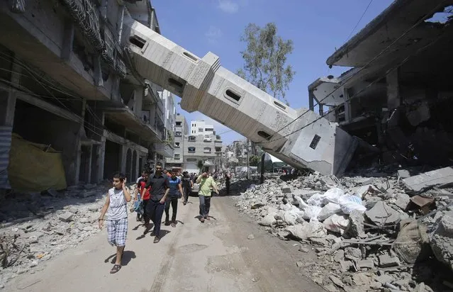 A collapsed minaret is seen as Palestinians leave after performing Friday prayers at the remains of a mosque, which witnesses said was hit by an Israeli air strike during a seven-week Israeli offensive in Gaza City August 29, 2014. An open-ended ceasefire, mediated by Egypt, took effect on Tuesday evening. (Photo by Ibraheem Abu Mustafa/Reuters)