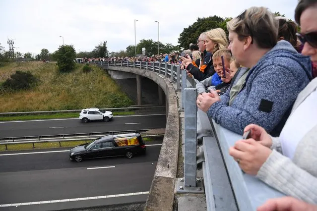 Members of the public stand on a bridge, in Kinross, overlooking the M90 motorway, pay their respects as they wait for the hearse carrying the coffin of Queen Elizabeth II to be driven to Edinburgh to lie at rest, on September 11, 2022. Queen Elizabeth II's coffin will travel by road through Scottish towns and villages on Sunday as it begins its final journey from her beloved Scottish retreat of Balmoral. The Queen, who died on September 8, will be taken to the Palace of Holyroodhouse before lying at rest in St Giles' Cathedral, before travelling onwards to London for her funeral. (Photo by Andy Buchanan/AFP Photo)