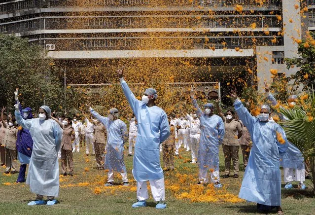 An Indian Air Force helicopter showers flower petals on the staff of INS Asvini hospital in Mumbai, India, Sunday, May 3, 2020. The event was part the Armed Forces' efforts to thank the workers, including doctors, nurses and police personnel, who have been at the forefront of the country's battle against the COVID-19 pandemic. (Photo by Rajanish Kakade/AP Photo)
