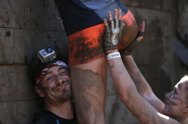 Participants climb over a wall at the “Tough Mudder” endurance event series in Arnsberg September 6, 2014. Competitors who took part in the endurance event saw themselves having to overcome various military style obstacles. (Photo by Ina Fassbender/Reuters)