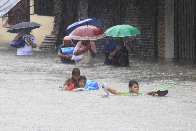 People carry their belongings as they wade through a flooded street after tropical storm Fung-Wong battered metro Manila September 19, 2014. (Photo by Erik De Castro/Reuters)