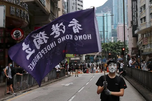 A masked anti-government protester holds a flag supporting Hong Kong independence during a march against Beijing's plans to impose national security legislation in Hong Kong, China on May 24, 2020. Hong Kong police fired tear gas and water cannon to disperse thousands of people who rallied on Sunday to protest against Beijing's plan to impose national security laws on the city. (Photo by Tyrone Siu/Reuters)