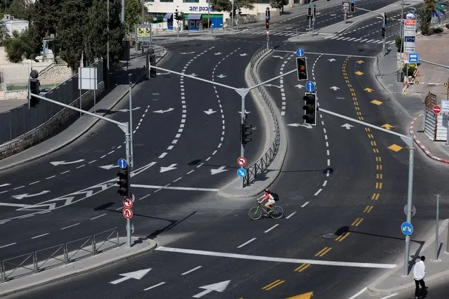 A person rides a bicycle on the deserted main highway from Jerusalem to Tel Aviv on Yom Kippur, the Jewish day of atonement and the holiest day in the Jewish calendar, in Jerusalem on October 5, 2022. (Photo by Ammar Awad/Reuters)