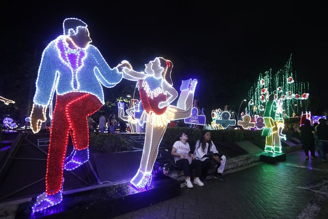 People enjoy Christmas lighting decorations in Cali, Colombia on December 6, 2023. The traditional Bulevar del Rio Cali is the place chosen for Cali residents and visitors to enjoy the lights that adorn the space, with figures alluding to salsa. (Photo by Ernesto Guzman/EPA/EFE)