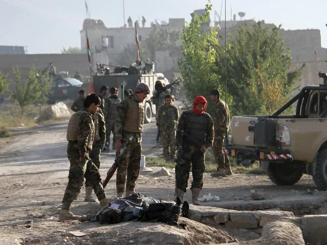 Afghan National Army (ANA) soldiers stand over the body of a Taliban insurgent outside a prison in Ghazni, Afghanistan, September 14, 2015. Taliban insurgents stormed a prison in the central Afghan city of Ghazni early on Monday, killing police and releasing hundreds of prisoners, police said. (Photo by Reuters/Stringer)