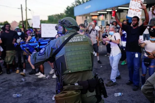 An Atlanta SWAT officer draws his weapon during a rally against racial inequality and the police shooting death of Rayshard Brooks, in Atlanta, Georgia, U.S. June 13, 2020. (Photo by Elijah Nouvelage/Reuters)