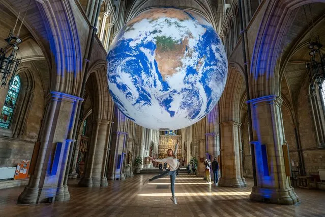 Visitors enjoy Gaia earth installation by Luke Jerram at Southwark Cathedral in London on October 11, 2022. The monumental internally-lit sculpture returns to the capital. UK artist Jerram aims to instil a sense of “overview effect” that astronauts experience when looking down at earth from space. (Photo by Guy Corbishley/Alamy Live News)