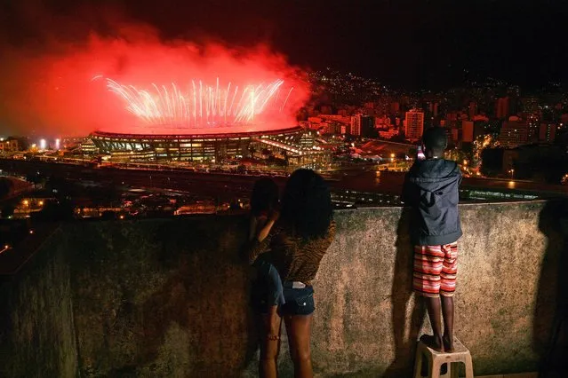 Residents from Mangueira favela watch fireworks over Maracana Stadium during the 2016 Olympics closing ceremony in Rio de Janeiro on August 21, 2016. (Photo by Carl De Souza/AFP Photo)