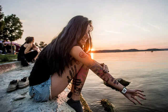 A girl washes the body paint off her arm on the shore of Lake Balaton during the coinciding Strand Festival and B.My.Lake Festival in Zamardi, 110 kms southwest of Budapest, Hungary, 24 August 2016. (Photo by Zoltan Balogh/EPA)