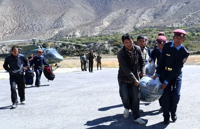 Nepalese police move the bodies of trekkers killed following a snowstorm and an avalanche to a plane to be transported to Kathmandu in Jomsom on October 17, 2014. Nepal's prime minister has pledged to set up a weather warning system after a major Himalayan snowstorm killed 32 people at the height of the trekking season, 17 of them tourists. (Photo by Skanda Gautam/AFP Photo)