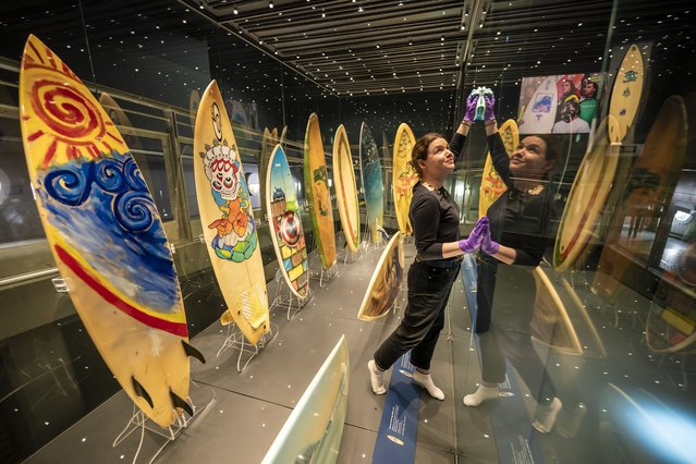 Staff clean and wipe all glass surfaces in large cabinets holding art-decorated surfboards, as final preparations are being made at the new exhibition – SURF! 100 years of waveriding in Cornwall, inside National Maritime Museum Cornwall, in Falmouth, UK on Tuesday, March 25, 2025. The exhibition, opening of Friday March 28th 2025, explores the history and cultural impact of surfing in Cornwall, celebrating a century of surfing and Coirnish surf culture. (Photo by Ben Birchall/PA Wire)