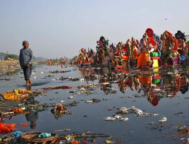 A man looks on as he collects items thrown by devotees as religious offerings next to idols of the Hindu god Ganesh, the deity of prosperity, after the idols were immersed on Sunday, in the waters of the Yamuna river in New Delhi, India, September 29, 2015. (Photo by Anindito Mukherjee/Reuters)