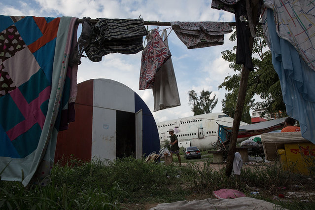 A young man brings goods into his home in a disused airplane on September 12, 2015 in Bangkok, Thailand. (Photo by Taylor Weidman/Getty Images)