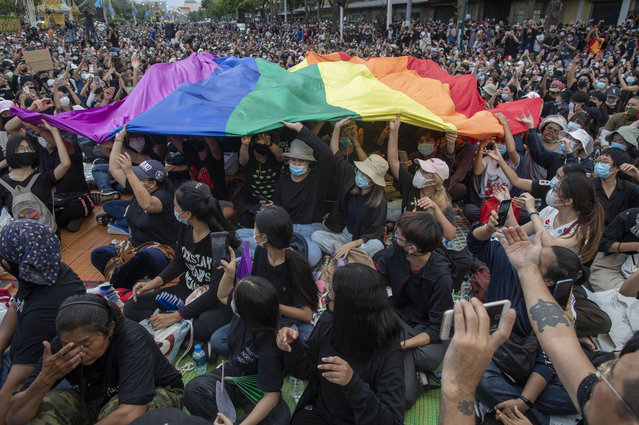 Pro-democracy activities display a LGBT flag during a protest at Democracy Monument in Bangkok, Thailand, Sunday, August 16, 2020. Protesters have stepped up pressure on the government demanding to dissolve the parliament, hold new elections, amend the constitution and end intimidation of the government's opponents. (Photo by Gemunu Amarasinghe/AP Photo)