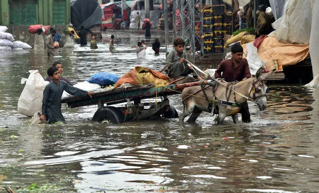 People make their way through a flooded road after monsoon rains in Lahore, Pakistan, 20 August 2020. According to reports, one person died in flood-related incident as heavy monsoon rain flooded several areas of Karachi causing traffic jams and power outages. (Photo by Rahat Dar/EPA/EFE/Rex Features/Shutterstock)
