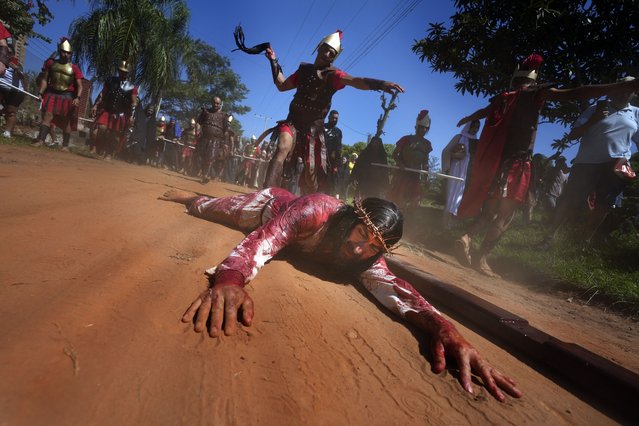 An actor, playing the role of Jesus Christ, is whipped by a Roman soldier as he falls during a Way of the Cross reenactment, as part of Holy Week celebrations, in Atyra, Paraguay, Friday, March 29, 2024. Holy Week commemorates the last week of Jesus' earthly life which culminates with his crucifixion on Good Friday and his resurrection on Easter Sunday. (Photo by Jorge Saenz/AP Photo)